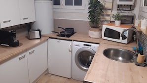 A compact kitchen with a washing machine, a microwave, a toaster, and a sink.