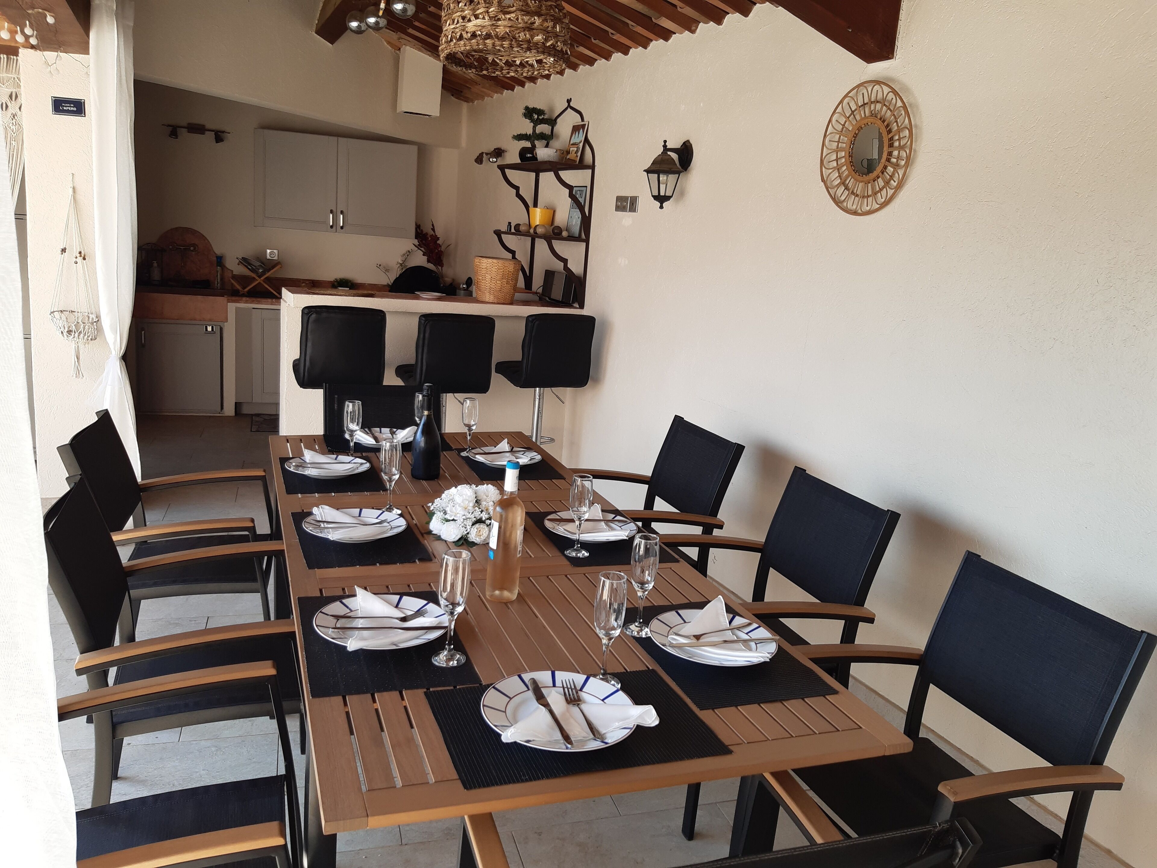 A dining area with a long table set for six, surrounded by black chairs.