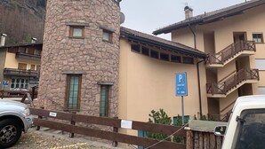 A building with a stone tower, a parking sign, and a multi-story structure with balconies.