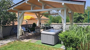 Un patio extérieur abrité, doté d’un jacuzzi, d’un espace salon et d’une structure en forme de pergola.