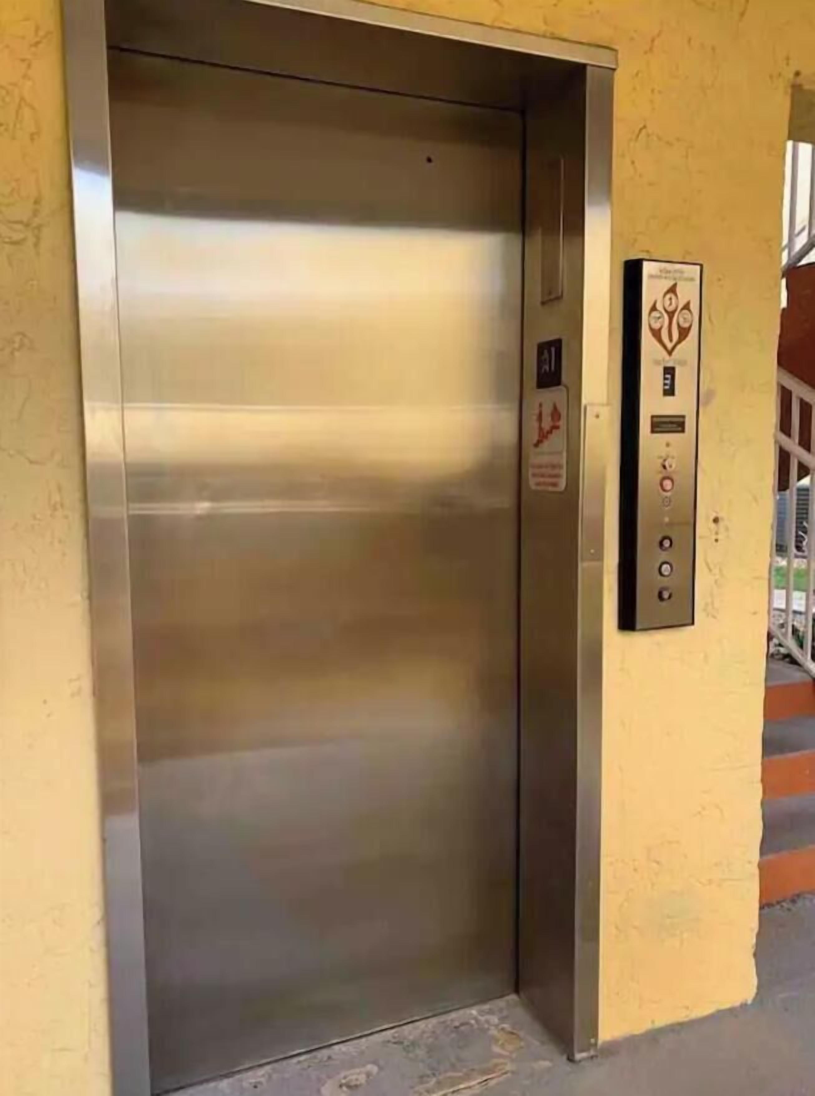Puerta metálica de ascensor con un panel de control a un lado.