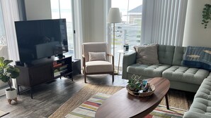 A modern living room with a flat-screen TV, a sofa, a chair, and a coffee table.