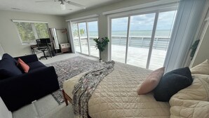 A bedroom with a large bed, a desk, and a view of the ocean.