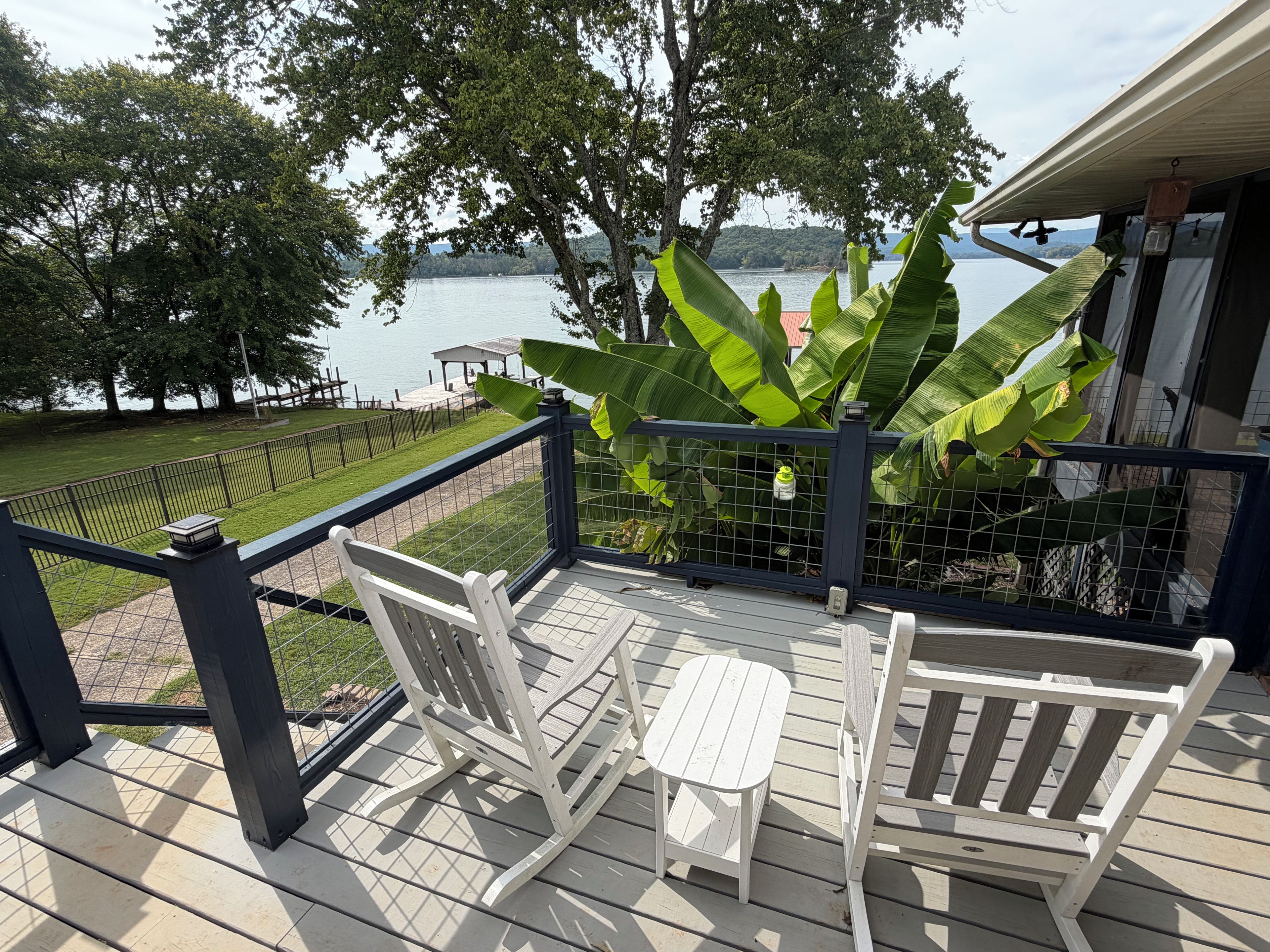 Una terraza de madera con dos mecedoras y vista a un lago.