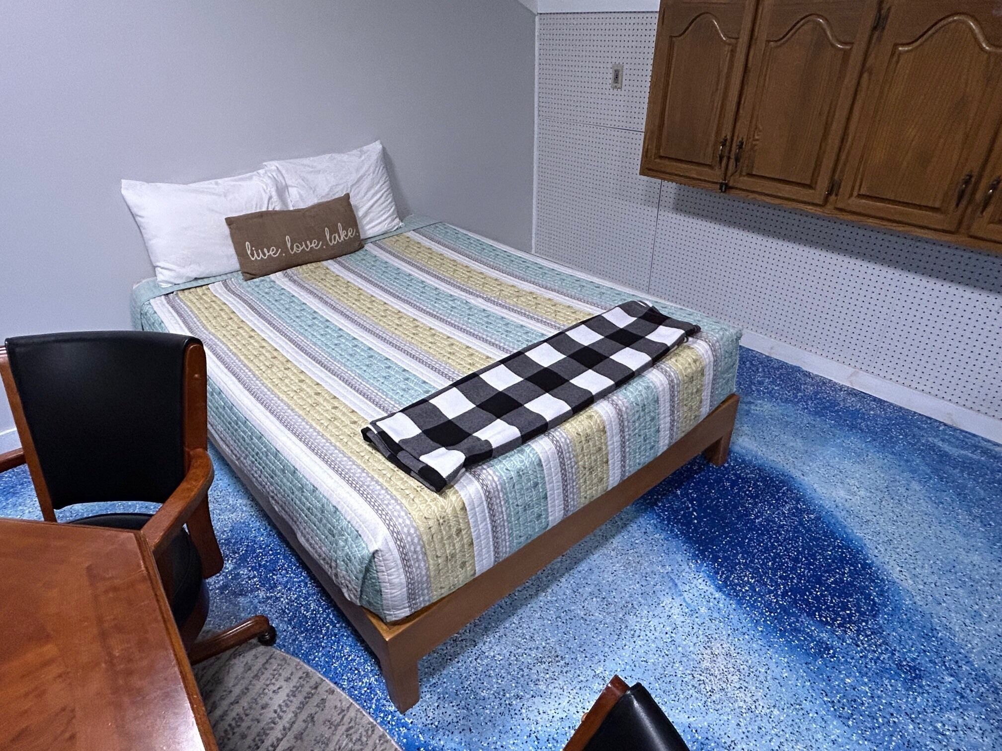 Ein Schlafzimmer mit einem Bett, einem Sessel, einem Holztisch und einem Schrank.