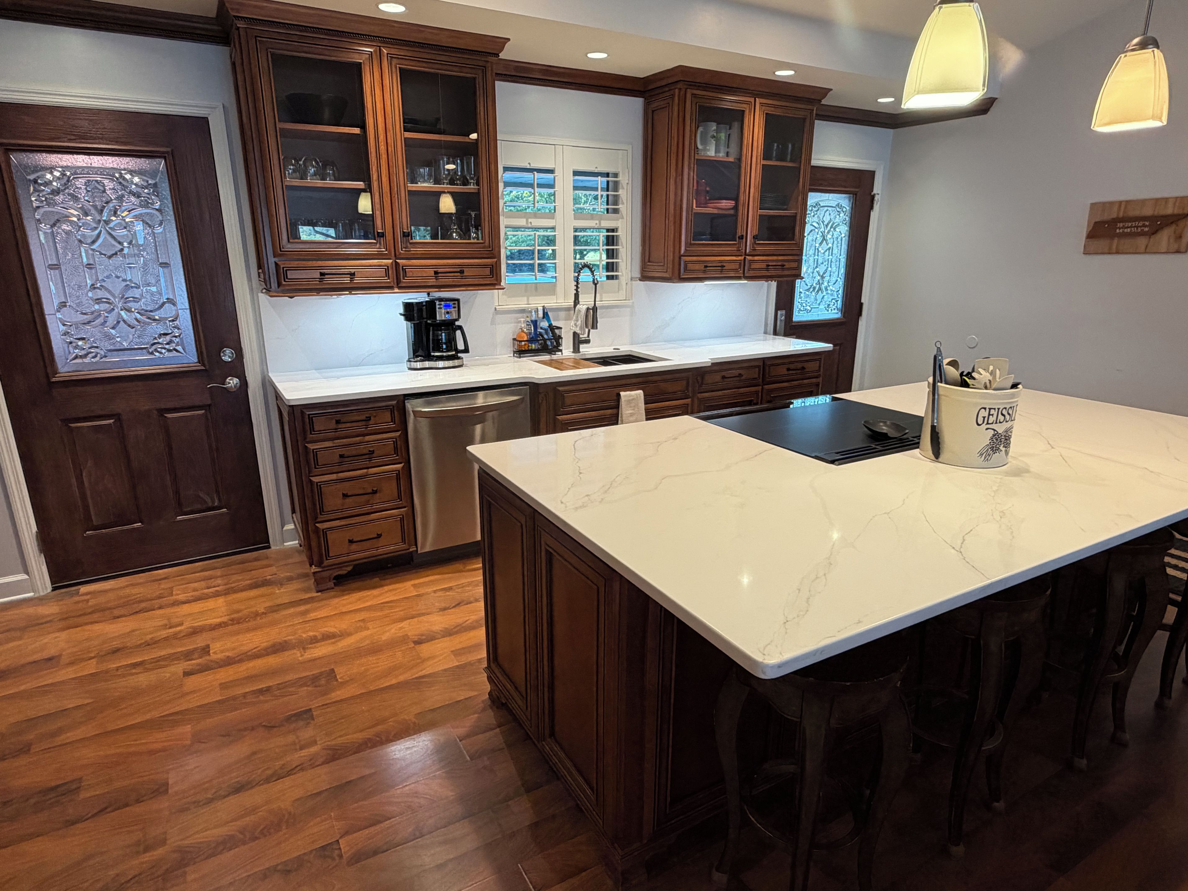 A kitchen with wooden cabinets, a marble countertop, and bar stools.