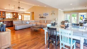 A spacious living area with a large sofa, a dining table, and a kitchen in the background.