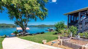 A lakeside property with a covered deck, a gazebo, and a view of the lake.