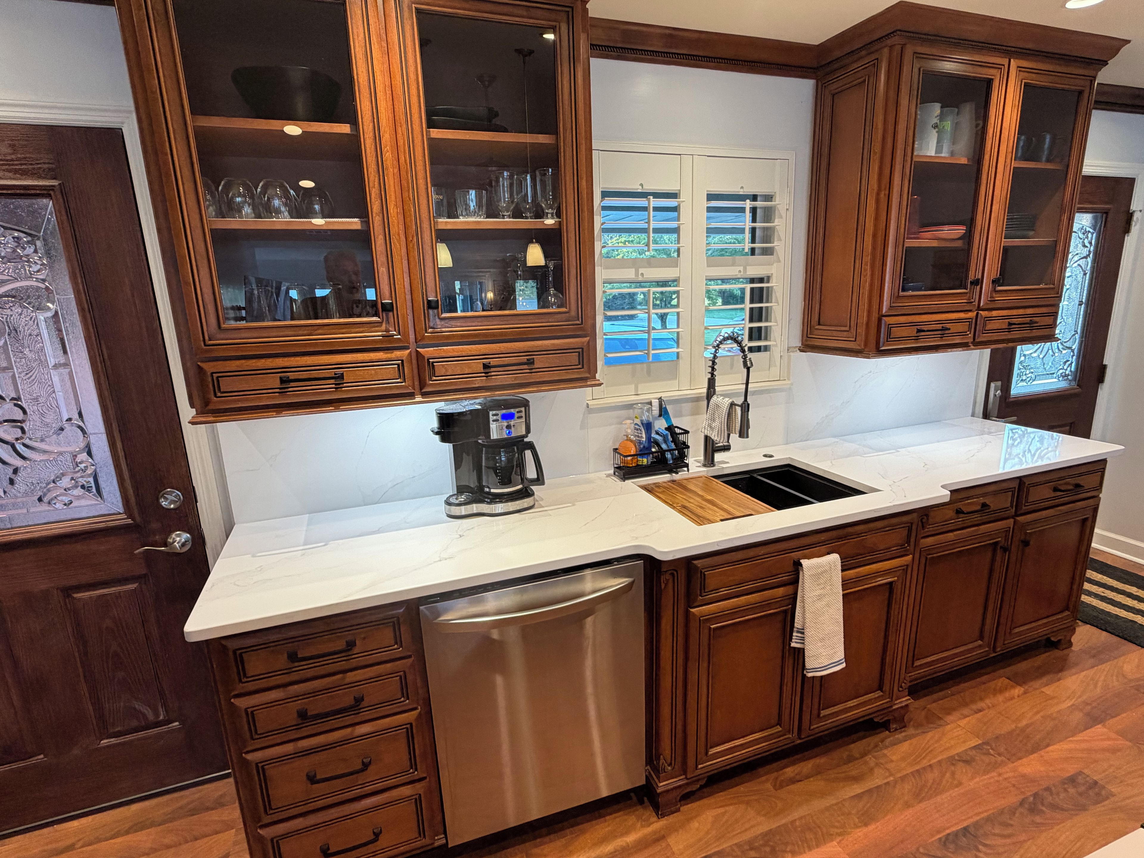 A kitchen with wooden cabinets, a stainless steel dishwasher, and a white countertop.