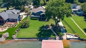 A lakeside property with a dock, a large tree, and multiple houses.
