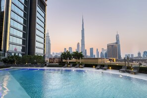 En pool med solstolar och utsikt över Dubais skyline, inklusive Burj Khalifa.