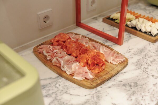 A wooden cutting board with sliced meats on a marble countertop.
