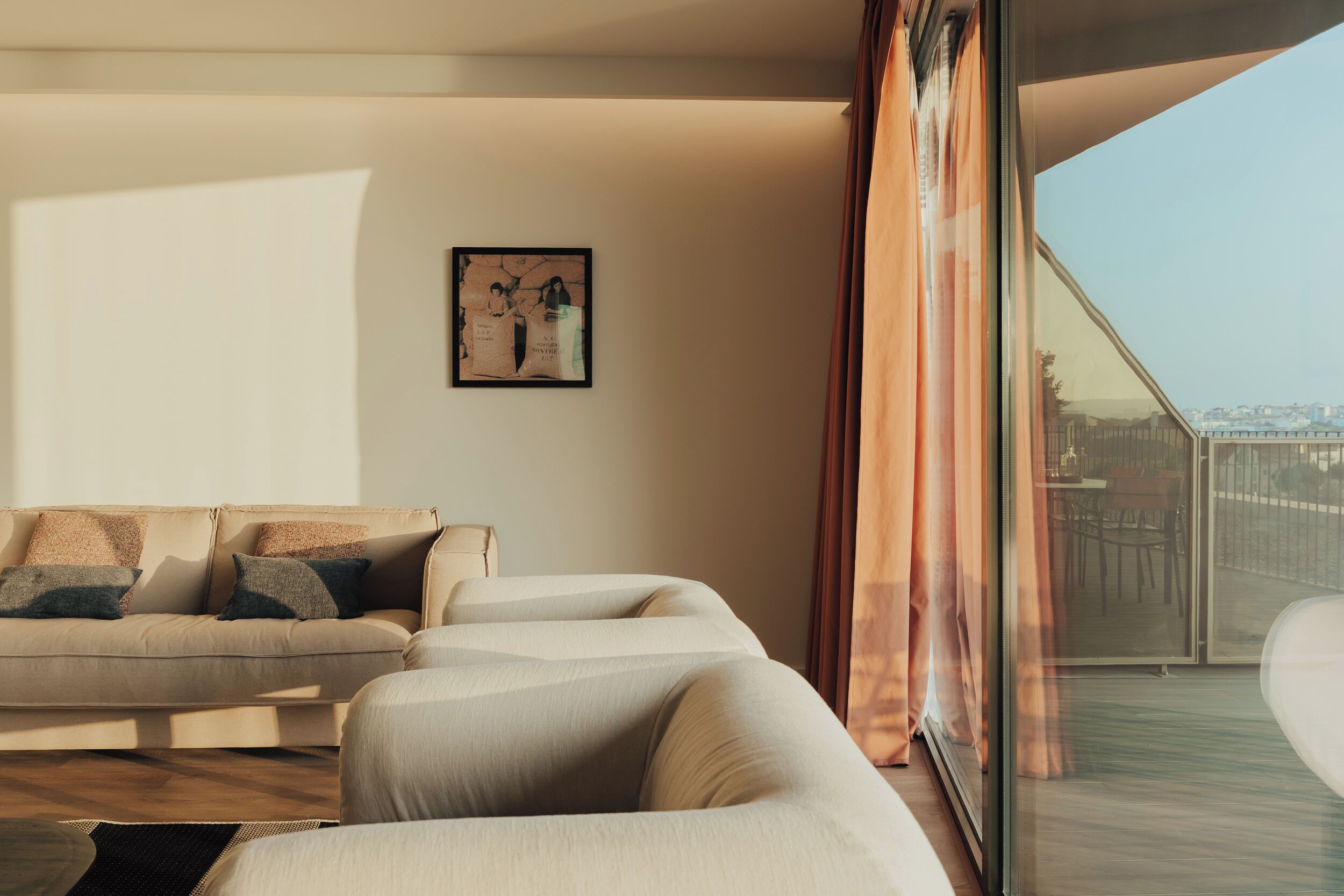 A modern living room with a sofa, a coffee table, and a large window with curtains.