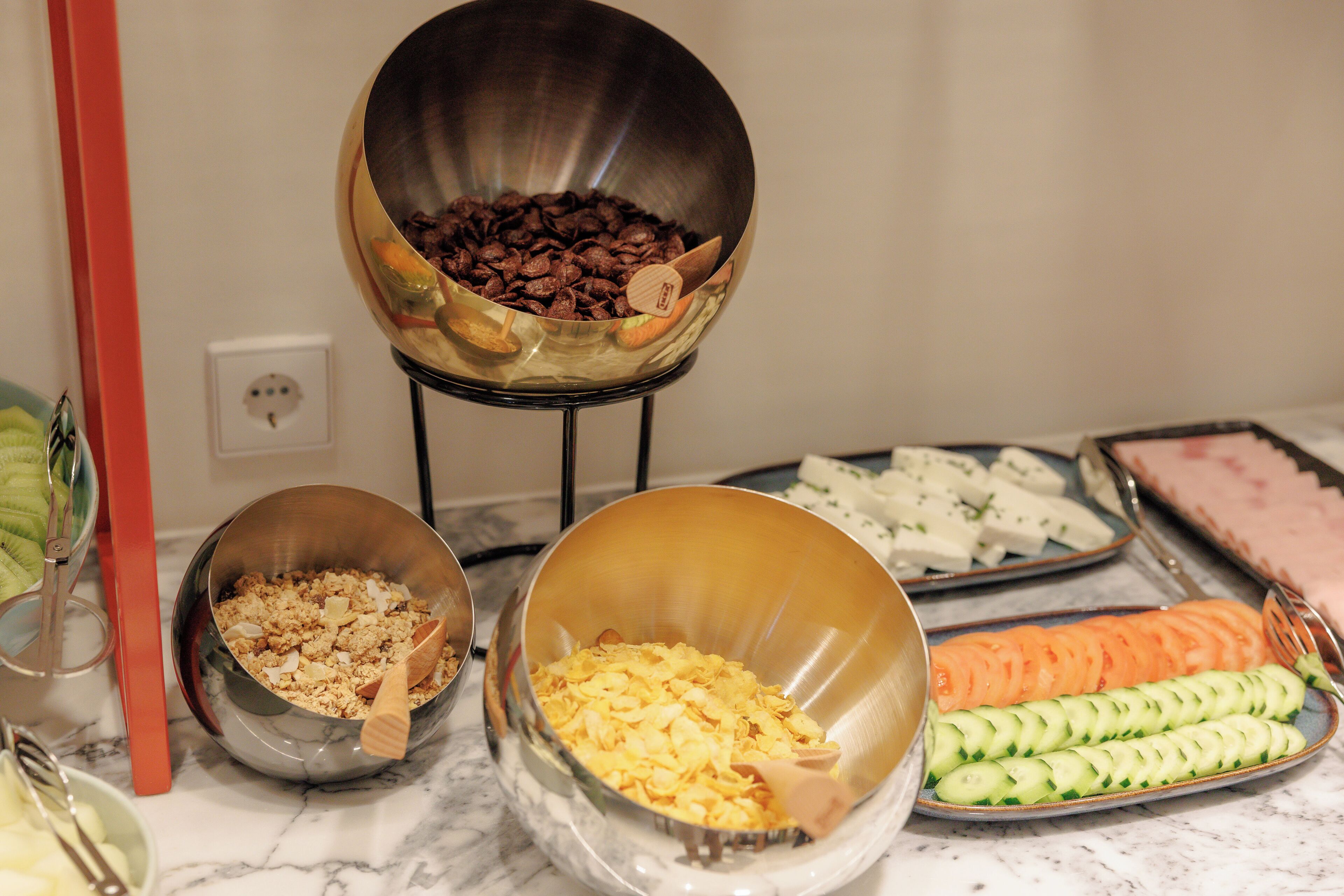 A buffet table with various food items including a bowl of chocolate chips, a bowl of cereal, and a tray of sliced vegetables.