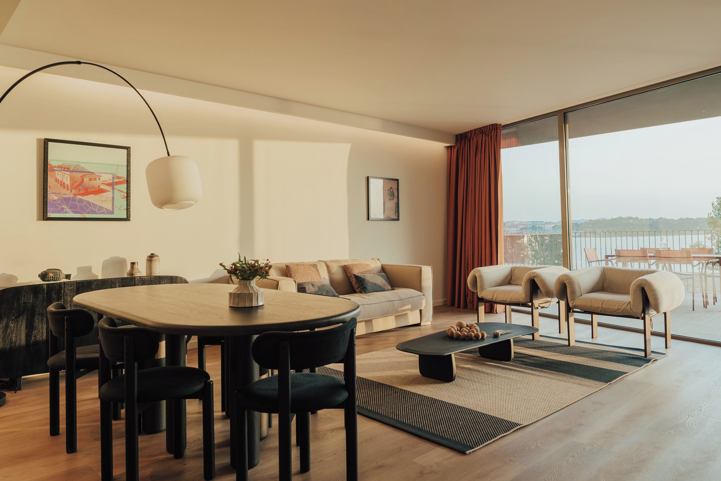 Sala de estar moderna com área de jantar, janelas amplas e vista para a cidade.