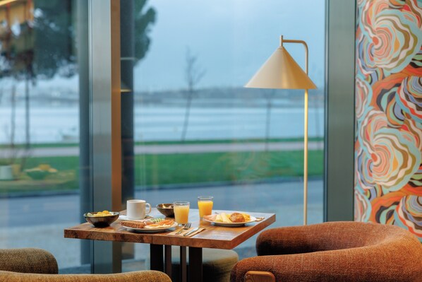 Una mesa de desayuno con vista a una masa de agua, una lámpara y una pared colorida.