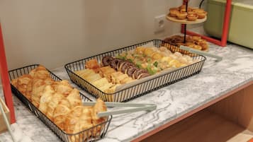 Un bufé con diversas opciones de panadería, incluyendo pasteles y panes.