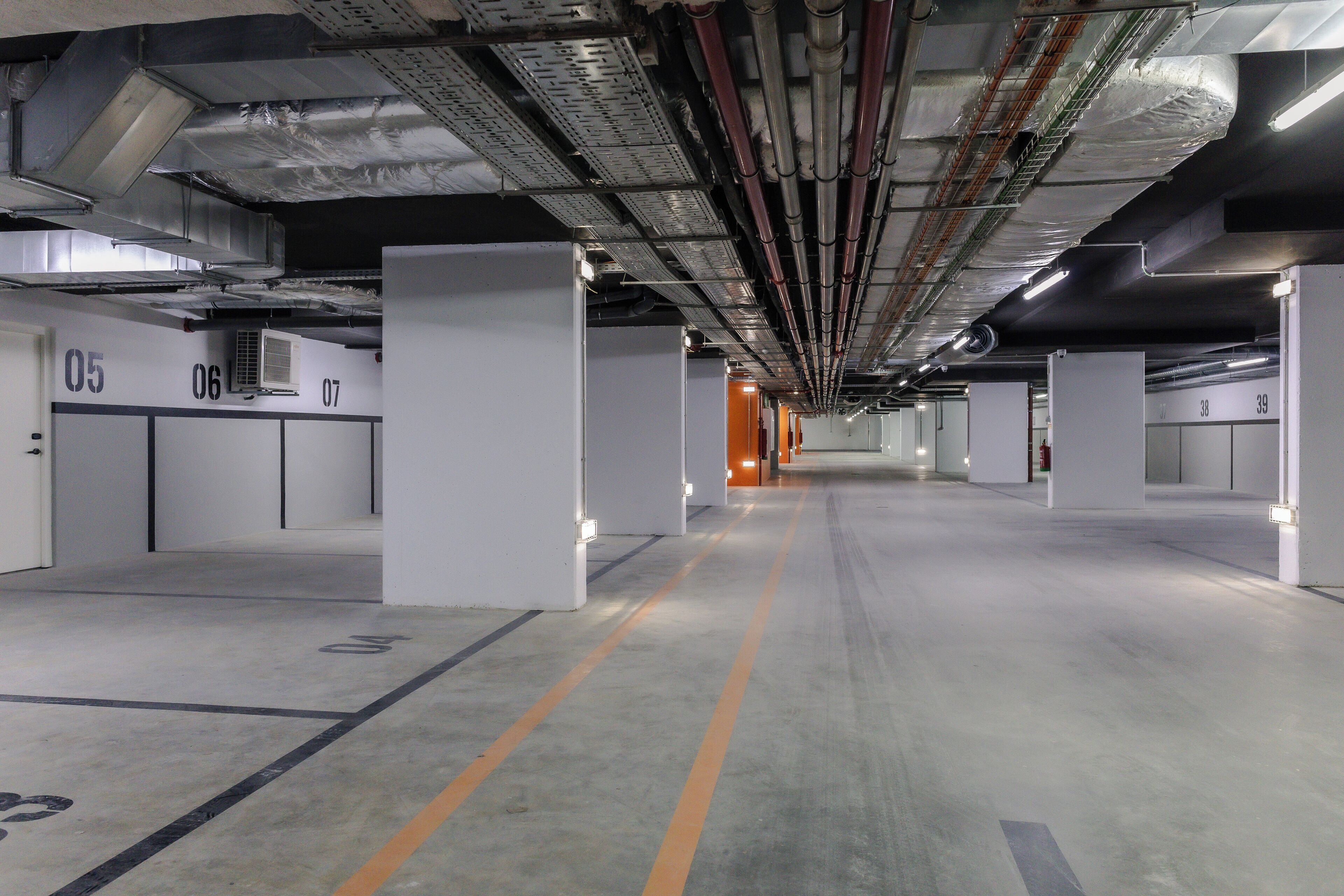Un parking souterrain propre et moderne, avec des places de stationnement clairement délimitées et une allée centrale.
