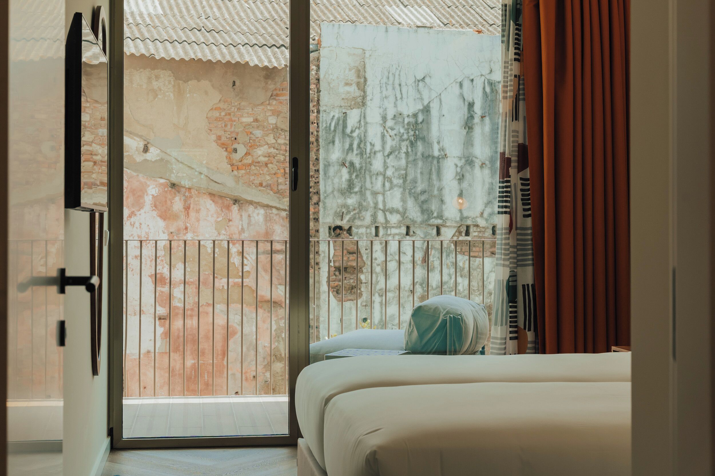 A hotel room with a balcony, a bed, and a view of an old building.