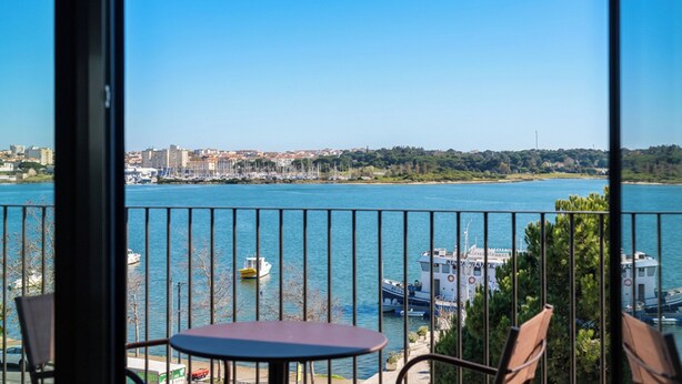 Un balcón con vista al agua, barcos y un paisaje urbano distante.