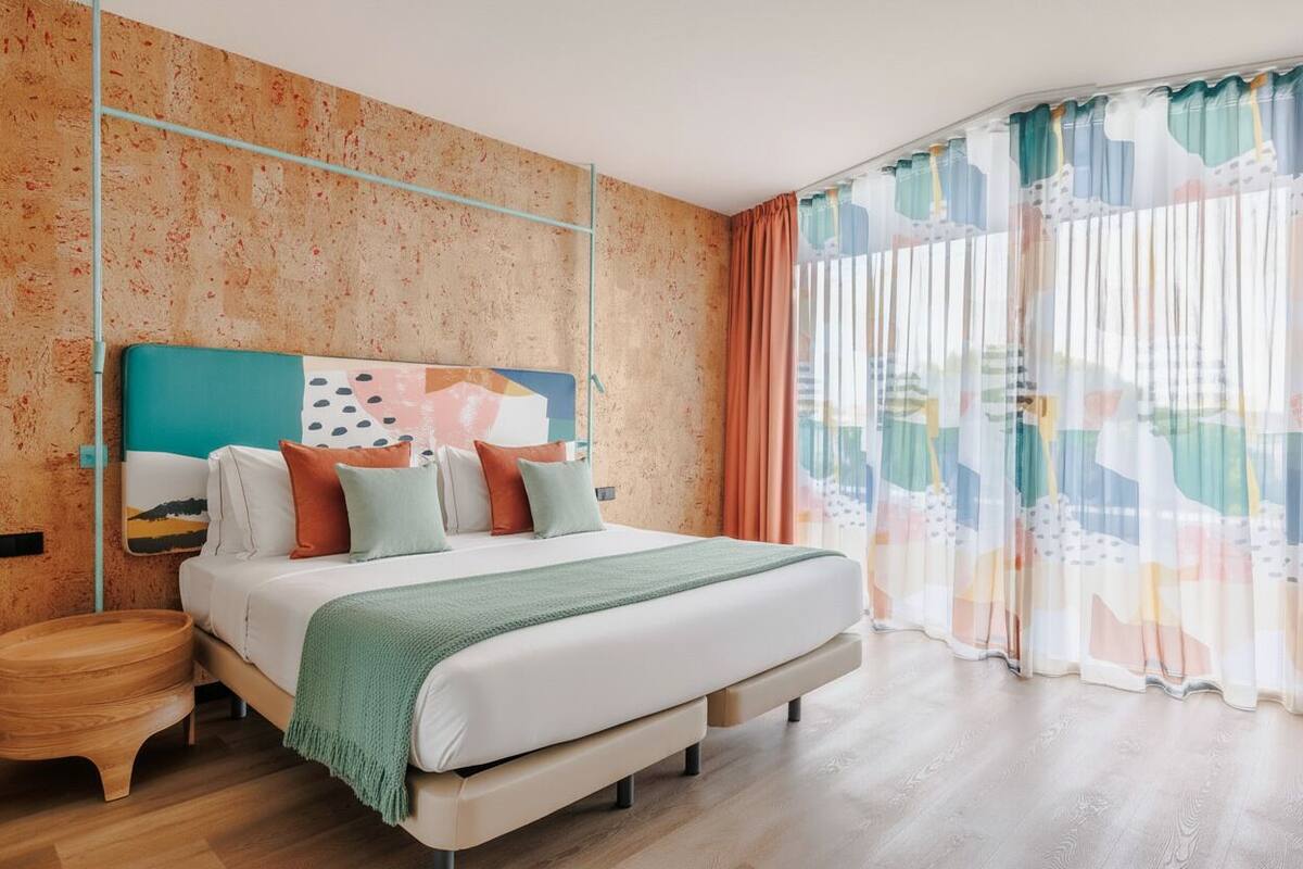 Een moderne slaapkamer met een groot bed, een houten nachtkastje en een stadsgezicht op de muur.