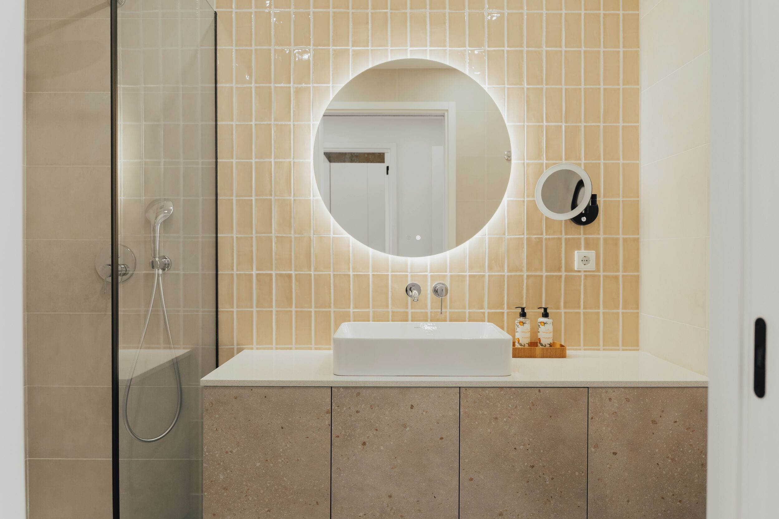 Ein Badezimmer mit einem weißen Waschbecken, einem runden Spiegel und einem Handspiegel.