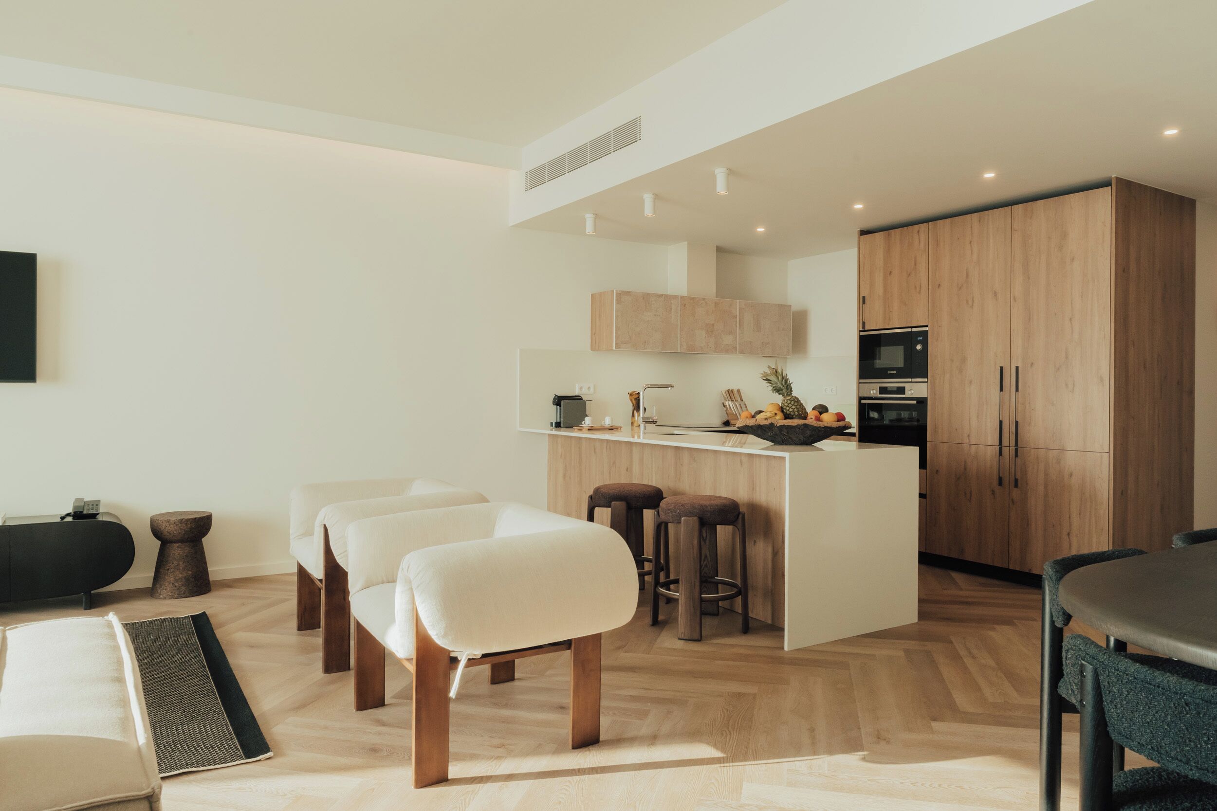 Une cuisine moderne avec des meubles en bois, un îlot central doté de tabourets et un coin repas avec une table et des chaises.