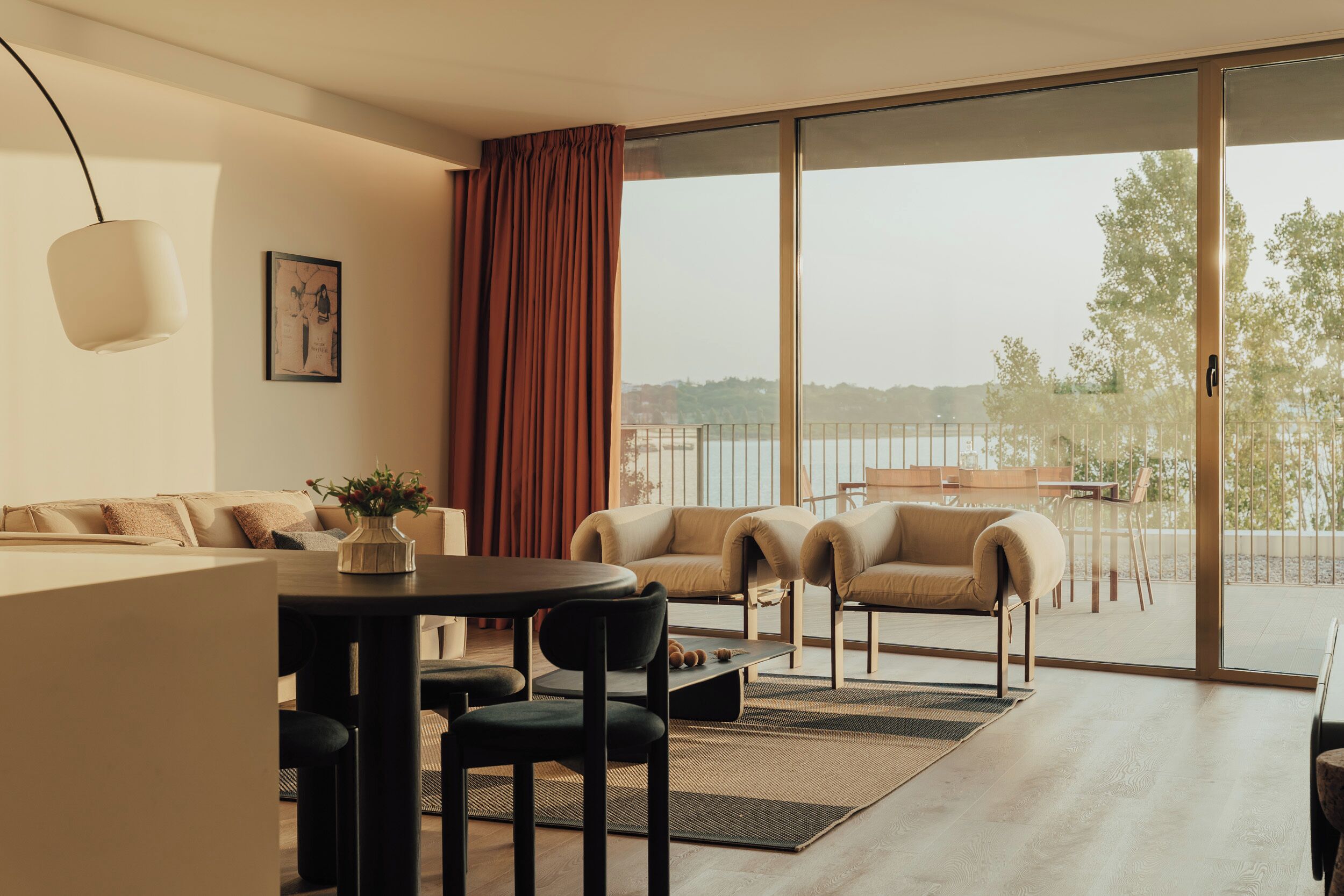 Un salon moderne avec un canapé, des fauteuils, une table à manger et une vue sur l’extérieur.