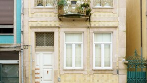 Un edificio de dos pisos con balcón, puerta y ventanas.