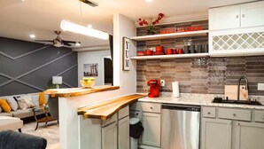Una cocina moderna con una isla de madera, electrodomésticos de acero inoxidable y un salpicadero con diseño geométrico.