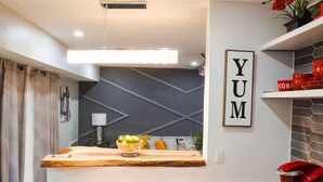 Una cocina moderna con encimera de madera, un tazón de fruta y un letrero que dice 'YUM'.
