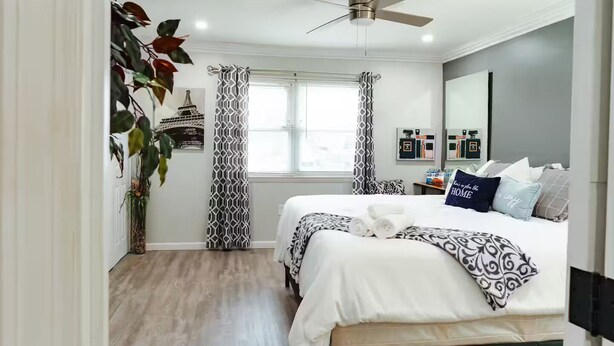 Un dormitorio moderno con cama, ventilador de techo y ventana con cortinas.