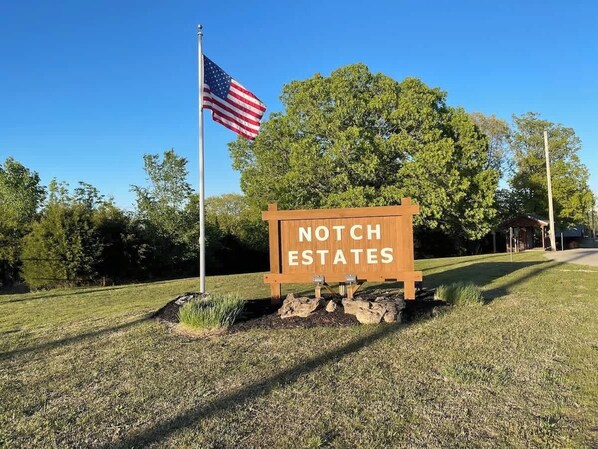 A wooden sign with "NOTCH ESTATES" written on it, an American flag, and a gazebo in the background.