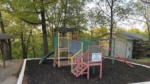 Une aire de jeux équipée d’un toboggan, de structures d’escalade et d’un panneau d’avertissement signalant les risques de blessures.