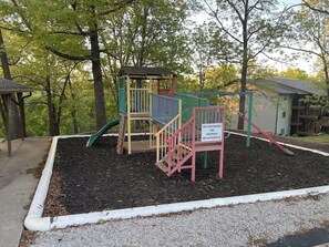 A playground with a slide, climbing structures, and a sign warning of potential injuries.