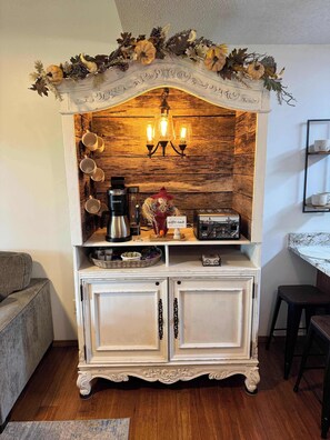 A white cabinet with a rustic backdrop, a coffee maker, a toaster, and a decorative sign. - Penthouse at Notch (First Responder Owner) (Branson West)