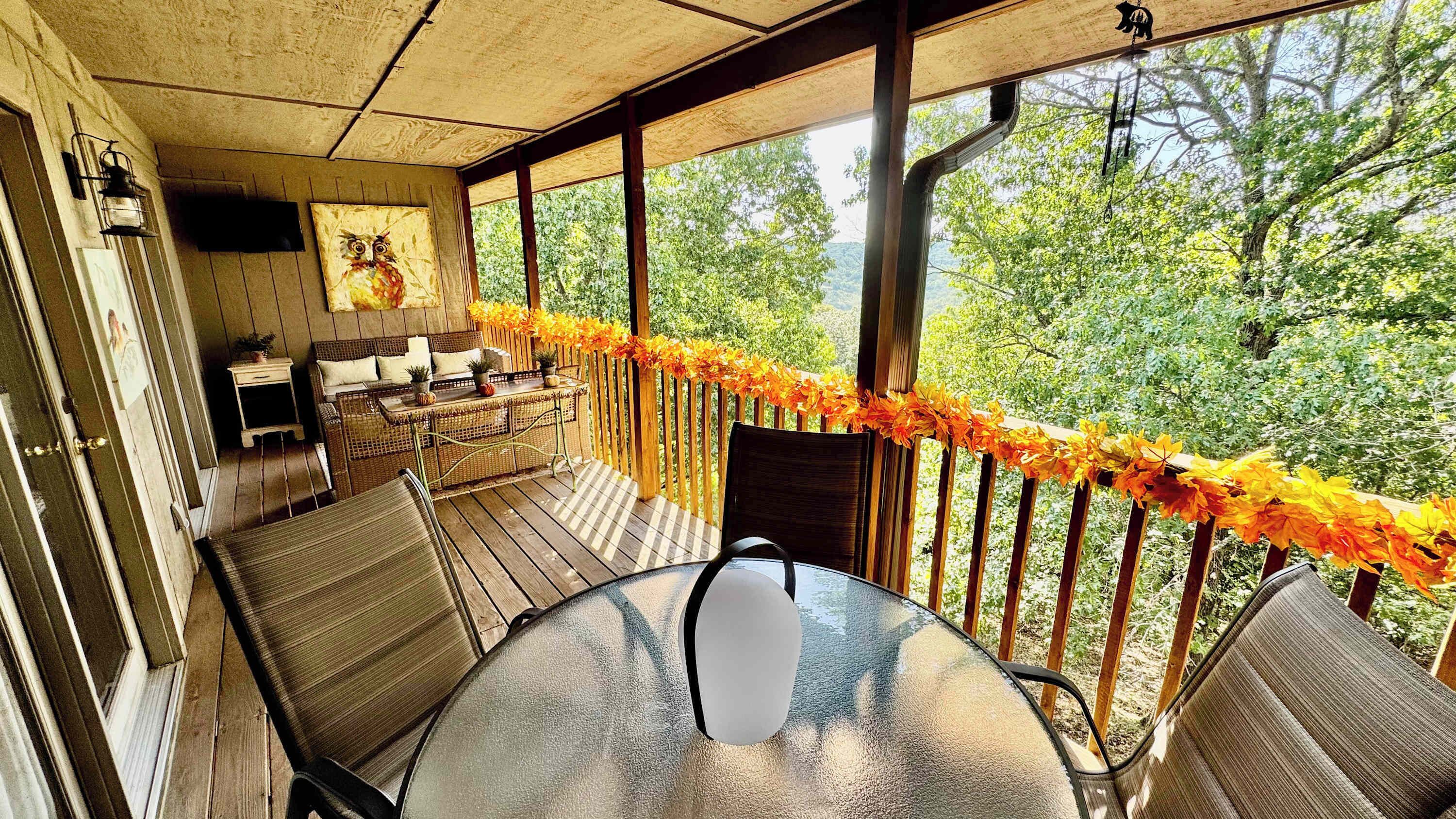 A covered outdoor seating area with a table and chairs, a sofa, and a decorative wall piece.