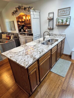 A kitchen with a granite countertop, wooden cabinets, a stainless steel sink, and a built-in oven. - Penthouse at Notch (First Responder Owner) (Branson West)