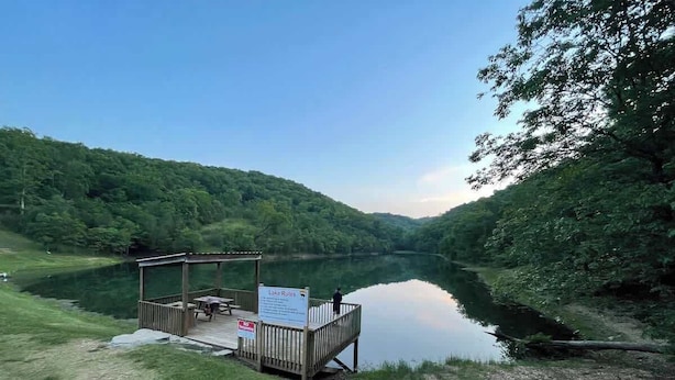 Une jetée en bois au bord du lac, dotée d’un espace de repos abrité et d’un panneau indiquant les règles à respecter sur le lac.
