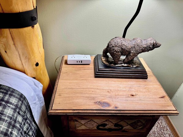 Una mesita de noche de madera con una regleta y una escultura de oso.