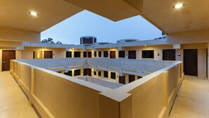 A modern hotel interior with a central courtyard, multiple rooms with balconies, and a view of the sky through the ceiling design. - Hotel Pakal 58 Centro (Mérida)