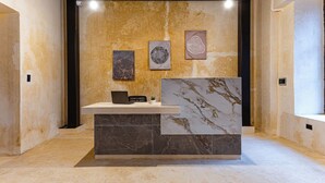 A reception area with a marble counter, a small plant, and three framed wall art pieces. - Hotel Pakal 58 Centro (Mérida)