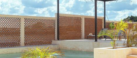 An outdoor seating area with a pool, a pergola, and a wooden fence.