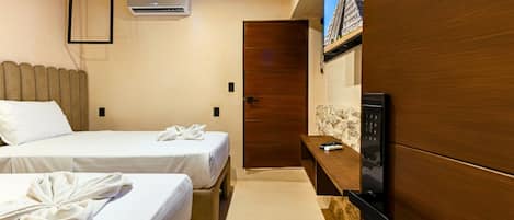 Habitación de hotel con dos camas, un armario de madera, televisor integrado y aire acondicionado.