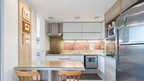A modern kitchen with white cabinets, a stainless steel refrigerator, and a tiled backsplash.