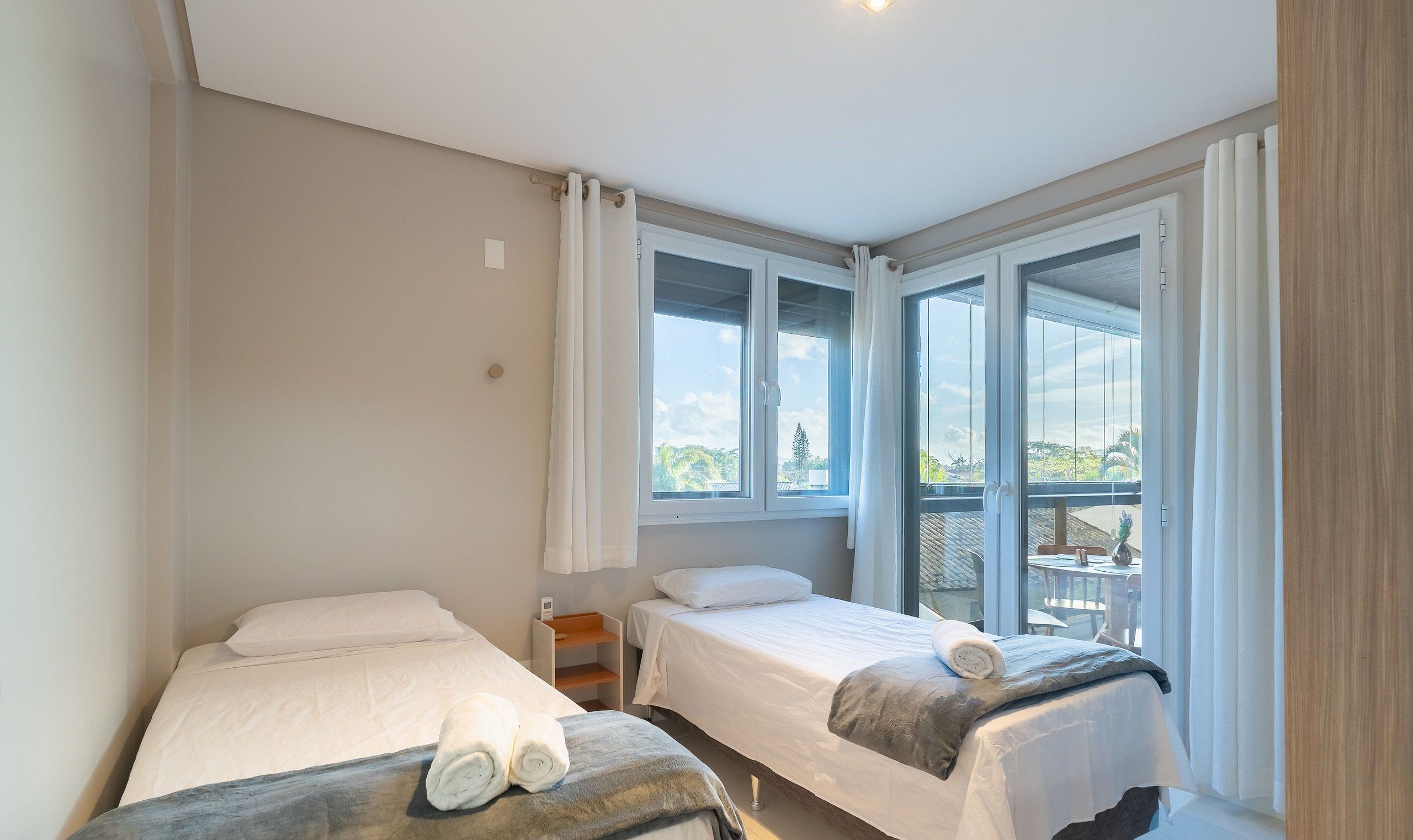 A hotel room with two beds, large windows, and a balcony.