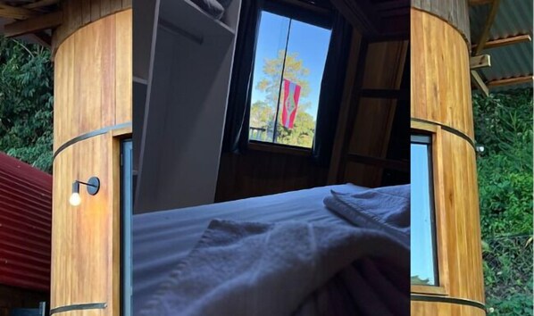 Une pièce en bois avec un lit, une fenêtre et une porte.