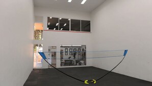 Una cancha de squash con una red, una escalera y una puerta que da a otra habitación.