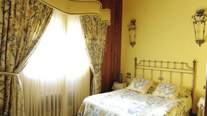 Une chambre avec un lit, des rideaux, une lampe fixée au mur et une table de chevet.
