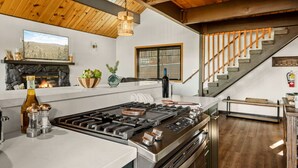 Una cucina moderna con isola centrale, un camino e una scala che conduce a un piano superiore.